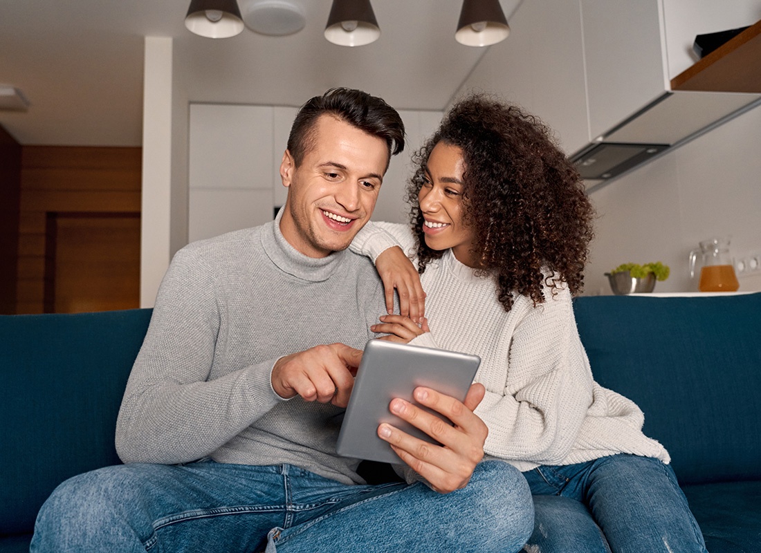Read Our Reviews - Portrait of a Cheerful Young Married Couple Sitting on the Sofa in the Living Room While Using a Tablet